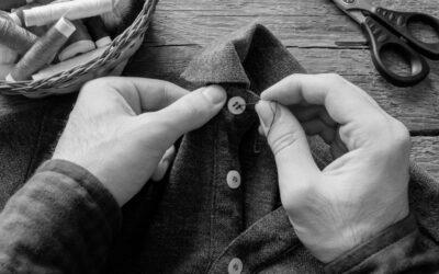 Un homme qui recoud un bouton sur une chemise