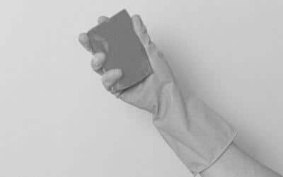 Main qui tient une éponge avec un gant de ménage